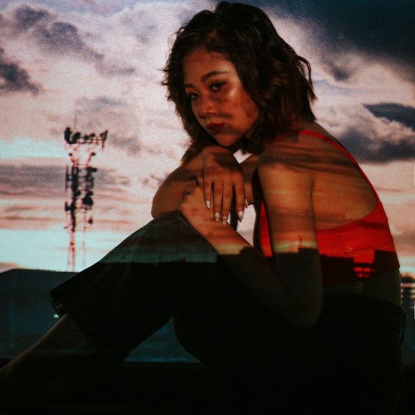 Person in a dynamic yoga pose against a dark, moody background.
